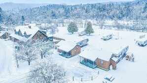 Un village enneigé, avec ses maisons traditionnelles en bois et une vue dégagée sur la forêt environnante.