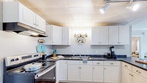 A modern kitchen with white cabinetry, a built-in oven, and a coffee maker.