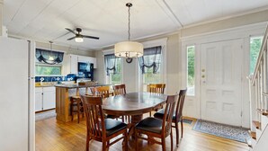 Un coin repas avec une table et des chaises en bois, un lustre et un ventilateur de plafond.