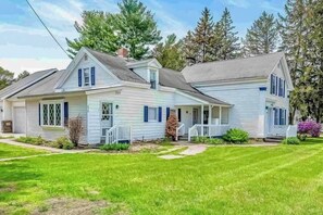 Ein zweistöckiges Haus mit Veranda, Garage und gepflegtem Rasen.