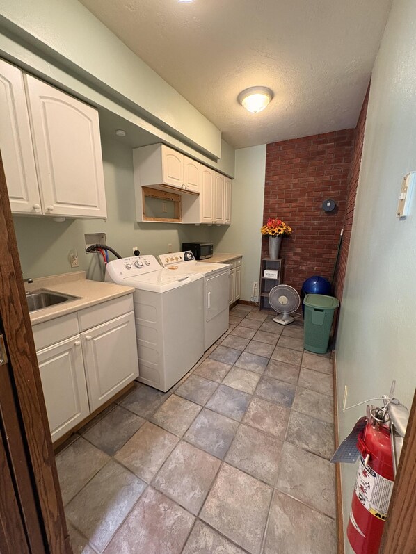 Cocina compacta con alacenas blancas, microondas, estufa y ventilador.