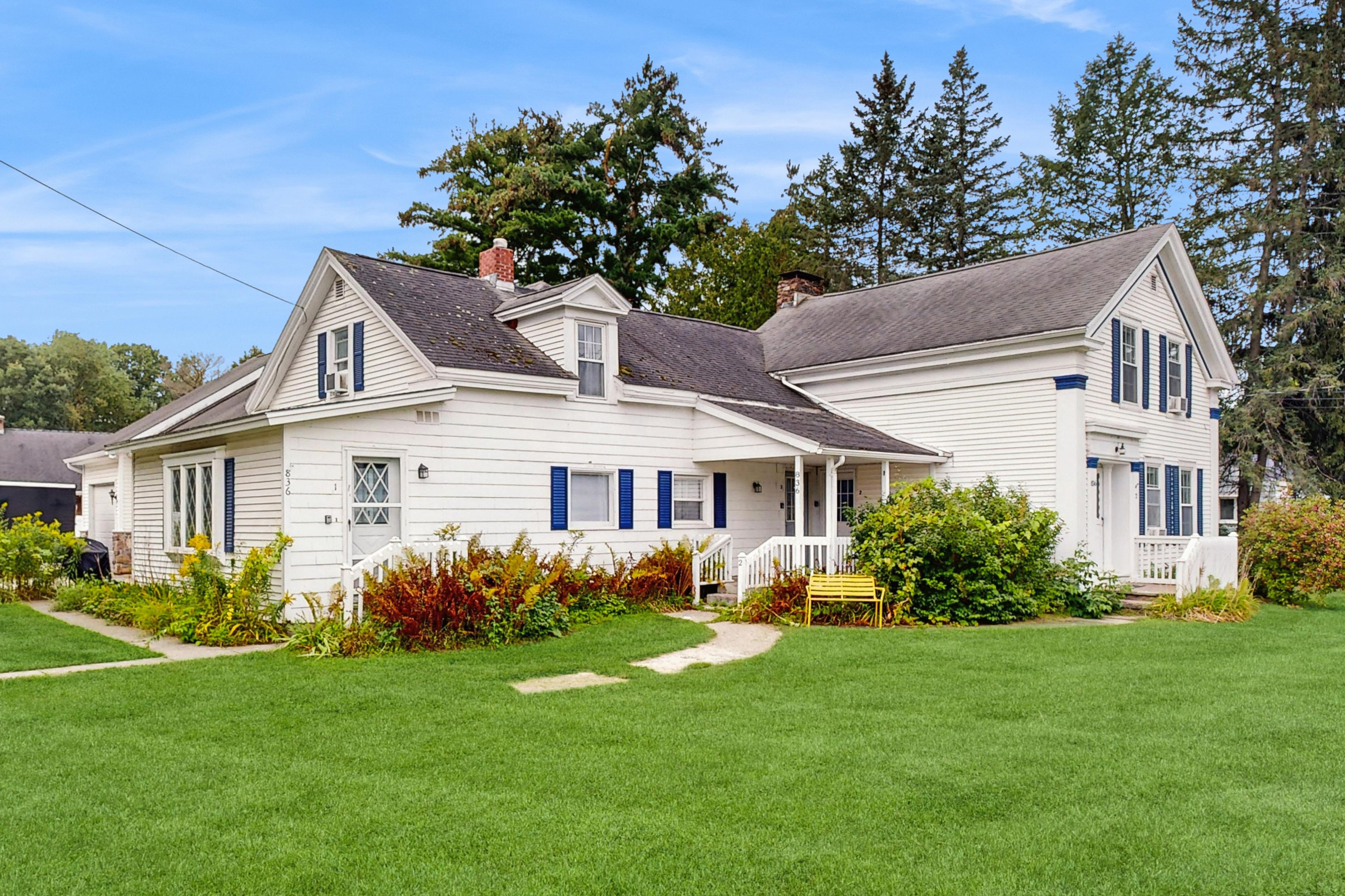 A two-story white house with a front porch and a small garden.
