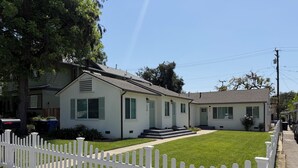 Une maison à deux étages, avec une clôture en bois peinte en blanc, une pelouse bien entretenue et une boîte aux lettres.
