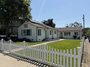 Une maison à deux étages, avec une clôture en bois peinte en blanc, une pelouse bien entretenue et une boîte aux lettres.