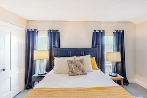 A neatly arranged bedroom with a bed, two bedside tables, and a window with curtains.