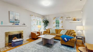 Un salon avec une cheminée, un canapé, une table basse et un tableau accroché au mur.