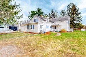 Une maison à deux étages avec un garage, une véranda et une pelouse bien entretenue.