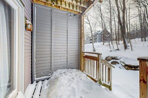 Eine überdachte Veranda mit Holzbalkon, einer Schiebetür und einer verschneiten Landschaft im Hintergrund.