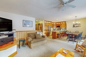 Ein Wohnzimmer mit einer Couch, einem Fernseher und einem Essbereich mit Stühlen und einem Tisch.