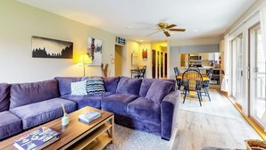 A living room with a sofa, coffee table, and a dining area with chairs and a table.