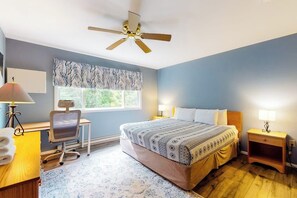 Ein Schlafzimmer mit Bett, Schreibtisch, Stuhl und Deckenventilator.