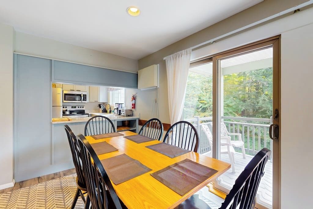 Un comedor con mesa y sillas, una cocina al fondo y un balcón con vistas.