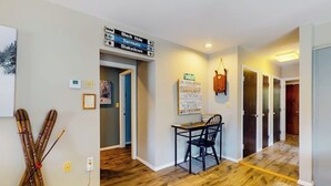 A hallway with wooden flooring, a dining area with a table and chairs, and a sign with directional arrows.