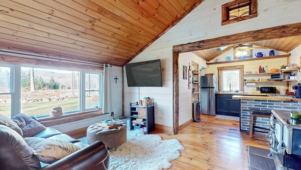 A cozy cabin interior with a living room, kitchen, and large windows. - Renovated historic cabin with mountain views, lake access, & electric fireplace (Jay)