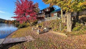 Un chalet au bord du lac, doté d’une terrasse, d’un foyer extérieur et offrant une vue sur le lac.