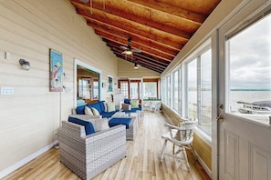 A spacious room with a wooden ceiling, large windows, and a view of the water. - Lakeside cottage w/ mountain views, canoes, firepit, enclosed porch, bbq, beach (Colchester)