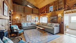 Un salon chaleureux avec des murs en bois, un grand canapé, un tapis à motifs et une table à manger.