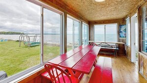 Une pièce dotée de grandes fenêtres, d’un plafond en bois et offrant une vue sur la mer.