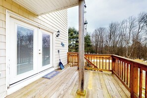 Eine Holzdielen-Terrasse mit Geländer, eine Tür mit Glasfenster und ein Metall-Laternenpfosten.
