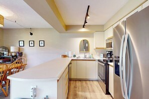 A compact kitchen with a central island, a built-in oven, and a refrigerator. - Cozy Ski-in/Ski-out condo w/ balcony, mountain views, gas fireplace, w/d, wifi (Jay)