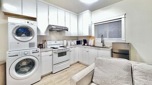 A compact kitchen with a washing machine, stove, oven, and refrigerator. - *AC/8mins-YVR/Private Bathroom Suite/Separate Entry/Free Parking/Near Skytrain (Richmond)