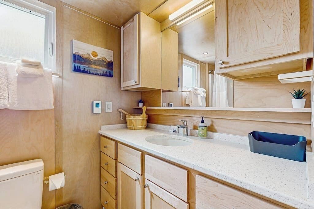 A bathroom with wooden cabinets, a sink, a mirror, and a towel rack.