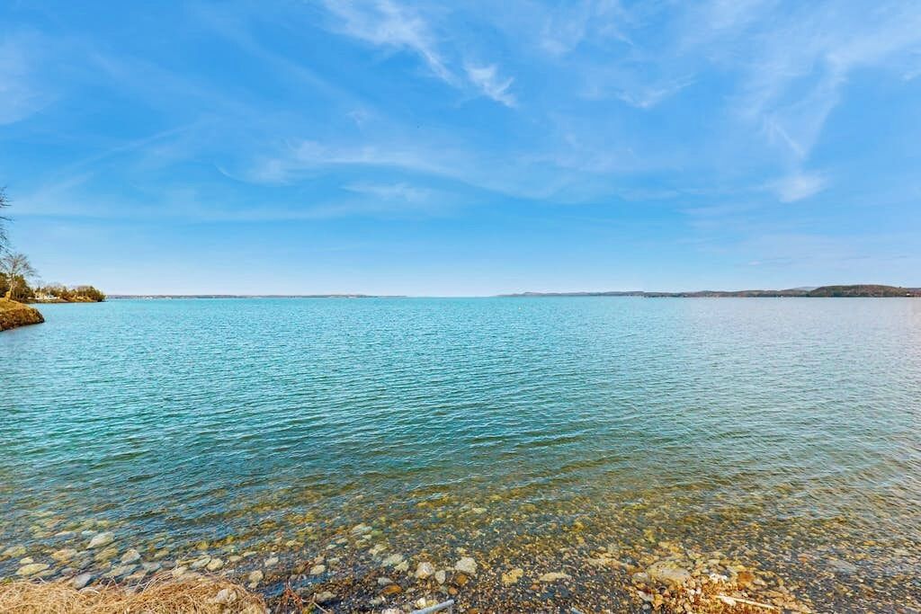 A clear view of a lake with a rocky shoreline and distant land.