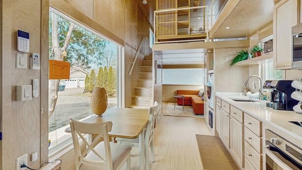 Una cocina moderna con comedor, una escalera y vistas al exterior.