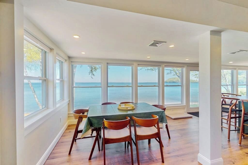 Un espace repas comprenant une table et des chaises, de grandes fenêtres et une vue sur la mer.