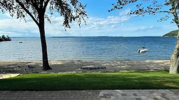 Une vue sur le lac avec un bateau, une zone herbeuse et une promenade dallée.
