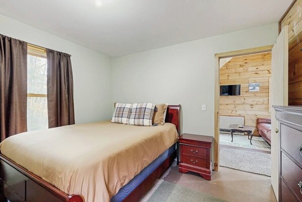Une chambre à coucher comprenant un lit, une table de chevet, une commode et un panneau mural en bois.
