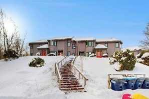 Ein mehrstöckiges Gebäude mit einer Treppe, die zum Eingang führt, umgeben von Schnee.