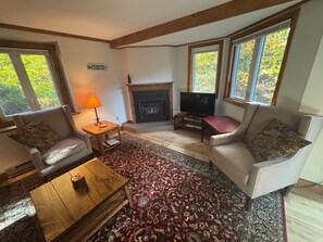 A living room with a fireplace, two sofas, a coffee table, and a television.