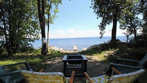 A campsite with two chairs facing a grill and a view of the water.