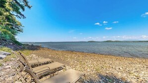 Une plage de galets avec des chaises longues et une vue dégagée sur l’eau.