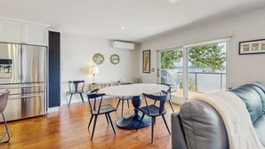 Une cuisine moderne équipée d’appareils électroménagers en acier inoxydable, un coin repas avec une table ronde et des chaises, et un balcon avec vue.