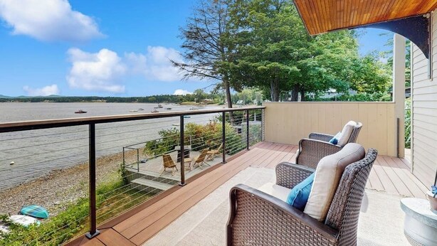 Un balcon agrémenté de meubles en osier, avec vue sur un lac et un plafond en bois.