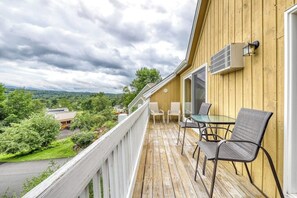 A wooden deck with outdoor seating, a white railing, and a view of the surrounding landscape. - Sleek condo with shared pool, tennis court, sauna, and hot tub (Stowe)