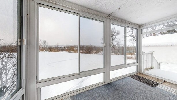 A covered porch with large windows, a white railing, and a doormat. - Cozy, Dog-Friendly Home w/ a Large Yard plus Free WiFi & a Private Washer/Dryer (Stowe)