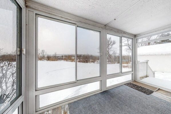 A covered porch with large windows, a white railing, and a doormat. - Cozy, Dog-Friendly Home w/ a Large Yard plus Free WiFi & a Private Washer/Dryer (Stowe)