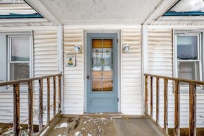 A two-story building with a blue door, white siding, and a wooden porch railing. - Cozy, Dog-Friendly Home w/ a Large Yard plus Free WiFi & a Private Washer/Dryer (Stowe)