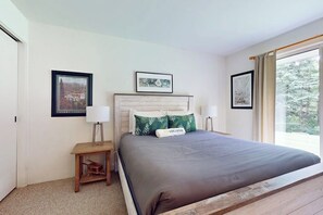 Ein Schlafzimmer mit Bett, Nachttisch, Lampe und gerahmten Bildern an der Wand.