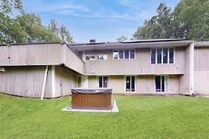 Ein zweistöckiges Haus mit einem überdachten Whirlpool im Garten.