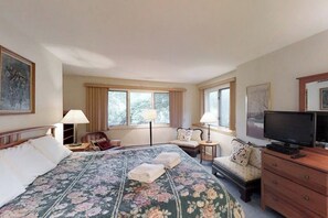 A hotel room with a large bed, two bedside tables, a television, and a sofa.