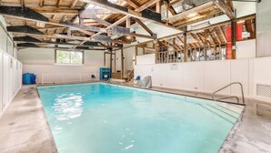 Ein überdachter Pool mit Betonboden, Holzbalken und einer weißen Wand mit einem Fenster.