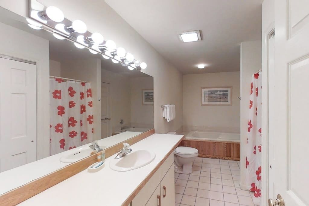 Un baño con espejo, lavabo e inodoro.