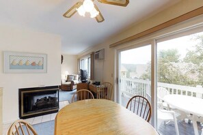 A dining area with a wooden table and chairs, a fireplace, and a balcony with a white railing.