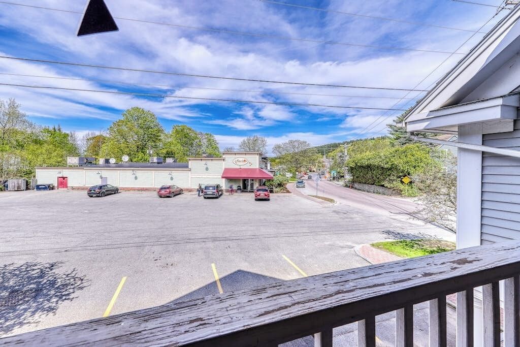 A parking lot with several cars, a building with a red awning, and a clear sky.