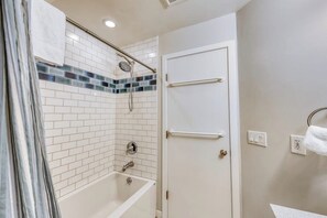 A bathroom with a shower, a bathtub, and a door.