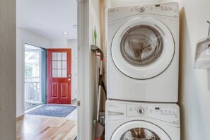 A laundry room with stacked washers and dryers, a red door, and a view to the outside. - Clean & Bright Condo near Slopes & Lakes with Amazing Walkable Locale (Stowe)